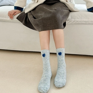 Détail de chaussettes en laine bleu-gris avec petit cœur en tricot et texture côtelée