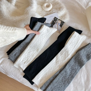 Close-up of thick knit leg warmers with diamond pattern in black, white and grey