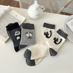 Detail of three pairs of cute animal patterned speckled socks in grey and off-white colors