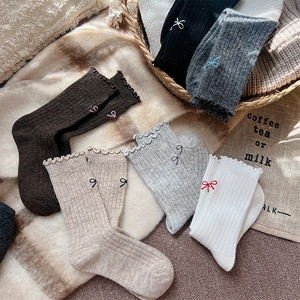 Detailed view of ribbed wool socks with lettuce edge trim and small bow embroidery details