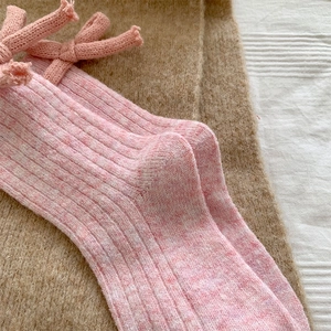 Close-up of pink wool socks with knitted bow decoration and ribbed texture