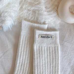 Close-up of white ribbed knit socks with Ann's for U. woven label on the cuff