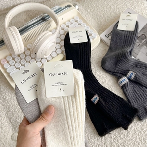 Detail of ribbed cotton socks with letter embroidery labels and cozy autumn home setup