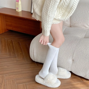 Detail of white argyle cashmere socks with ribbed cuffs and plush home slippers