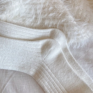 Close-up of cream white ribbed knit socks texture on soft faux fur and fabric background