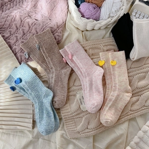 Gros plan détaillé de chaussettes en laine avec décor de cœur 3D en bleu, rose et brun