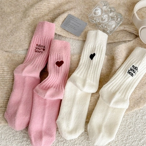 Detail of pink and white thermal knit socks with embroidered heart and text decoration