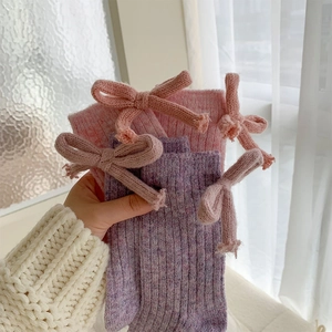 Detailed close-up of knitted wool socks featuring sweet bows and marled texture