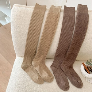 Detaillierte Strickstruktur von braunen Overknee-Kaschmir-Socken auf weißem Webpelz