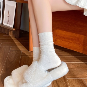 White heart textured knit mid-calf socks styled with plush faux fur slippers on wood floor