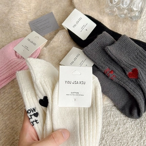 Close-up of pink and white knit socks with red heart embroidery and letter detailing