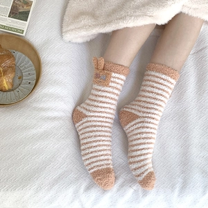 Detail of fuzzy coral fleece socks with orange stripes and cute 3D bunny ear accents