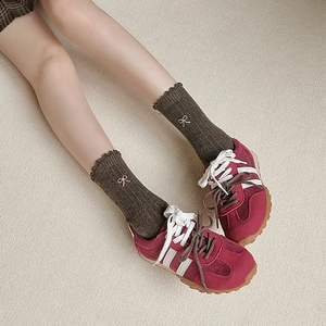 Detail of wool socks with bow embroidery and ruffle edges worn with retro red sneakers