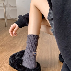 Detail of grey ribbed knit socks with distressed holes and a rectangular side patch