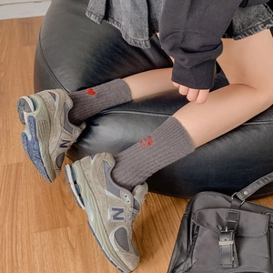 Close-up of pink warm socks featuring red heart embroidery and grey vintage sneakers