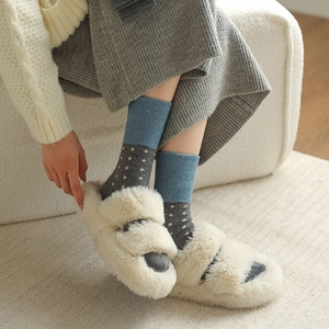 Détail de pantoufles en peluche beige avec des chaussettes en laine à pois de style rétro