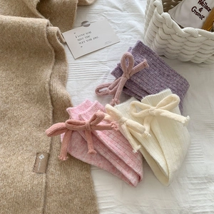 Detailed view of cozy knit wool socks with sweet bow accents in soft pastel colors