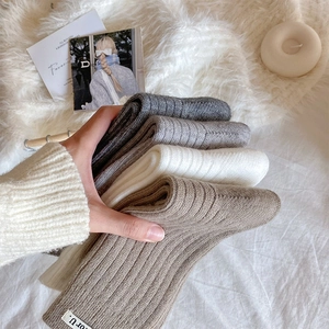 Close-up of thick rib-knit socks in neutral colors with stylish 'for U.' fabric label