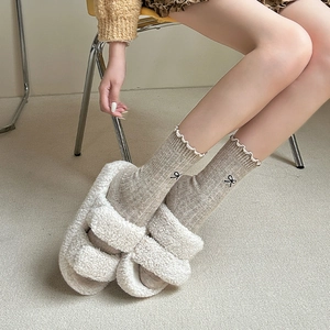 Close-up of wool socks with bow embroidery and ruffled edges with fleece slippers