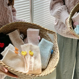 Gros plan de chaussettes en laine avec cœurs au crochet dans un panier rustique