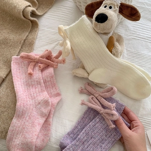Detailed knit texture of wool socks with decorative bows and plush puppy background