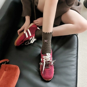 Detail of burgundy suede sneakers paired with coffee brown socks featuring pink bow embroidery