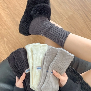 Detailed knit texture of vintage distressed socks with letter embroidery and holes