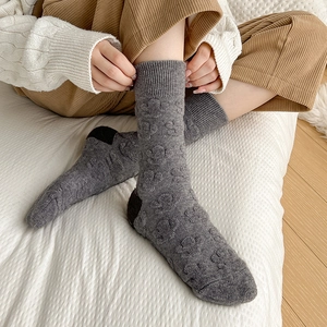 Detail of wool socks featuring raised heart patterns and contrast color heel design