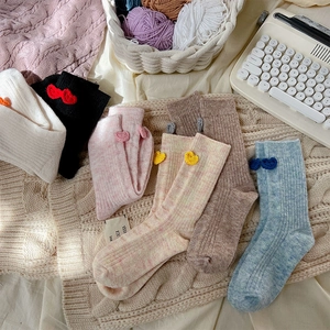 Détail de chaussettes en laine avec cœurs crochetés sur fond en maille douce