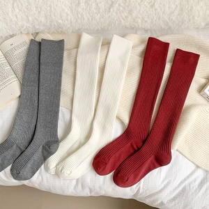 Three pairs of thick ribbed knit crew socks in grey, beige, and red for winter comfort