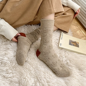 Detailed close-up of khaki wool socks featuring 3D cactus relief and red contrast heel