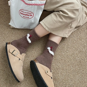 Detail of cozy winter puppy socks paired with beige suede mules and cork soles