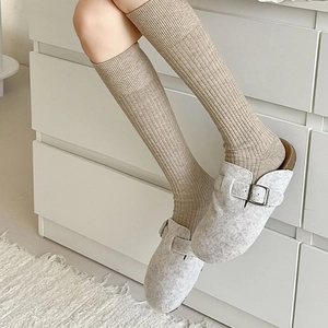 Detail of ribbed knit cashmere socks paired with grey felt mules for a cozy winter look