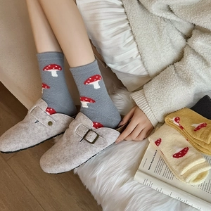 Detail of warm crew socks with mushroom embroidery paired with cozy grey felt mules