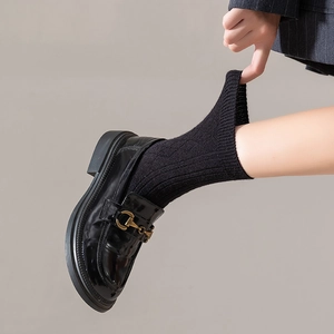 Close-up of black ribbed mid-calf socks with high elasticity paired with leather loafers