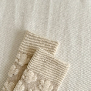 Macro shot of cream wool socks showing textured relief jacquard and ribbed cuff detail