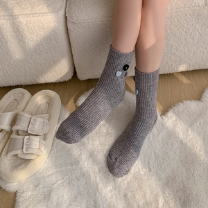 Gray rib-knit velvet mid-calf socks with decorative heart buttons on fuzzy white carpet