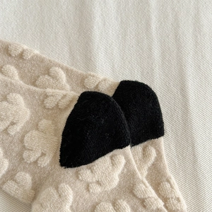 Detailed macro view of beige wool socks with embossed bear pattern and black heel