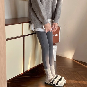 Detailed view of dark grey thermal leggings styled with striped socks and plush slippers
