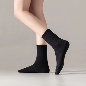 Detail of black diamond knit knee-high socks showing textured wool blend material