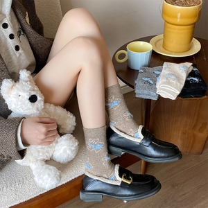 Detail of cute cat embroidery on warm knit socks with fuzzy white faux fur trim