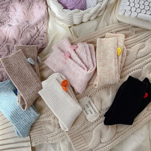 Détail de chaussettes en laine avec fleurs 3D aux couleurs pastel d'hiver douces