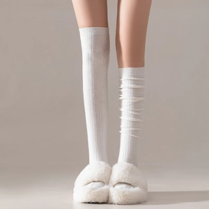 Close-up of white ribbed knit socks worn straight and slouched with plush slippers