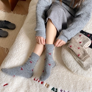 Macro detail of cozy knit wool socks with red hearts and blue pattern in gray finish