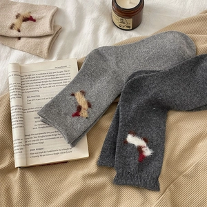 Detail of plush animal patch on grey warm knitted socks against cozy home decor