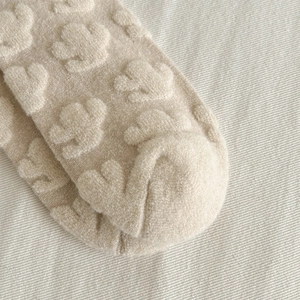Detailed macro view of cactus embossed texture on thick wool socks in cream beige tone