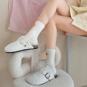 Gros plan de mules douillettes en polaire blanche avec sangle réglable pour un look maison