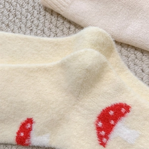 Close-up of fuzzy winter socks with cute red mushroom patterns and soft warm texture