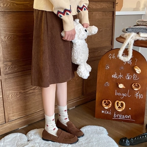Detail of cream wool socks with sheep pattern paired with brown suede loafers