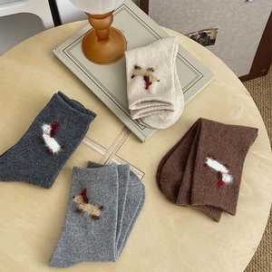 Detailed knit texture of cozy dog embroidered socks in four warm neutral tones